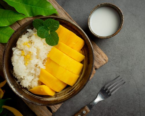 fresh ripe mango and sticky rice with coconut milk on dark background